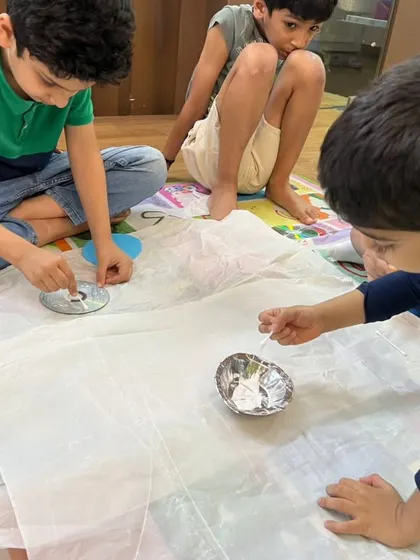 Summer camp is in session! These young scientists are focused on a chemical reaction experiment, carefully adding liquids to their bowls.