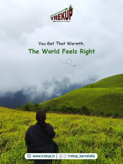 You get that warmth, the world feels right. A trekker sitting peacefully in a green meadow, soaking in the view.