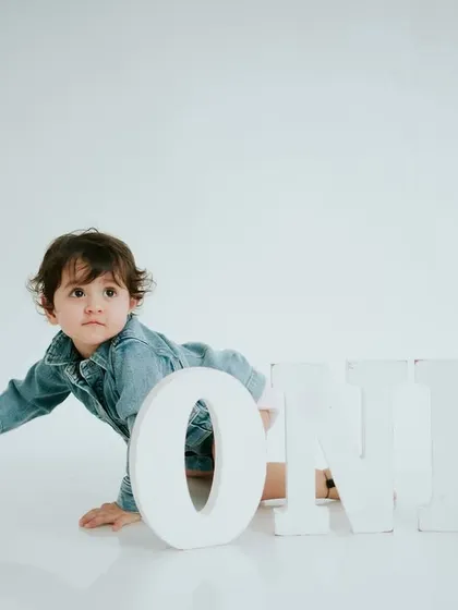 A curious pause during his crawl. The simple denim outfit gives this minimalist first birthday shoot a cool, modern feel.