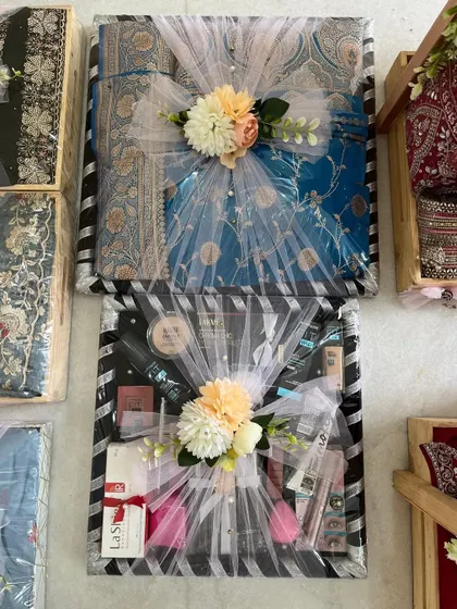 Dreamy wedding trousseau packing in black and white striped trays. The gifts are wrapped in delicate white tulle and adorned with floral bouquets, creating a chic and modern look.