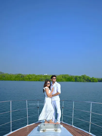 A beautiful wide shot of the couple standing at the bow of a boat, surrounded by blue water and green shores, perfect for a destination pre-wedding album.