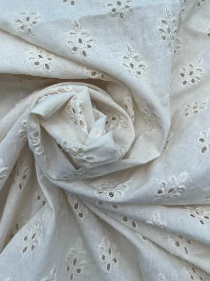 A beautiful off-white cutwork cotton fabric, perfect for creating sophisticated and breathable outfits. The intricate embroidery adds a touch of elegance.
