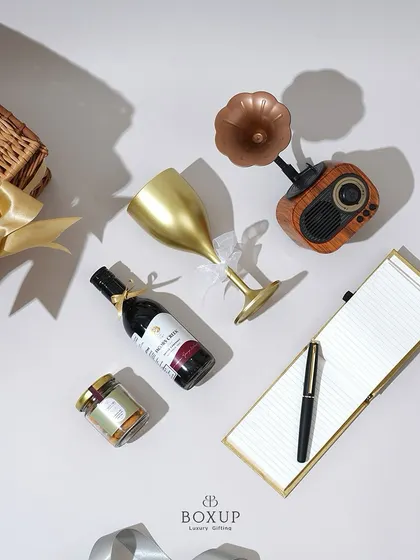 A top-down view of the "Vintage Dreams" hamper, showcasing the retro speaker, non-alcoholic wine, and golden notepad.