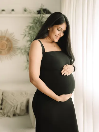A classic and elegant maternity portrait. The simple black dress creates a timeless silhouette, focusing all the attention on the beautiful shape of your baby bump.