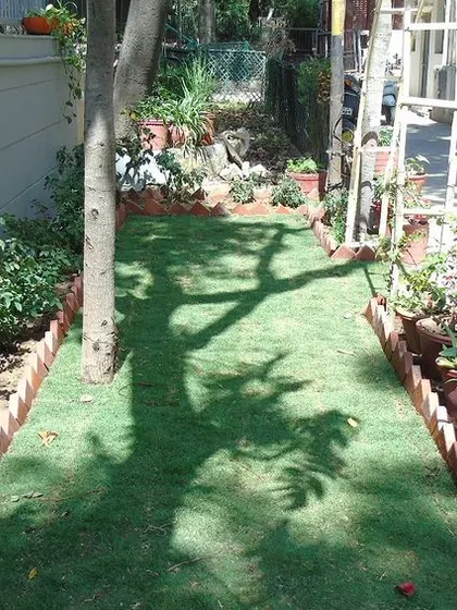 Another view of the backyard garden project. The narrow strip of lawn is bordered by colorful flower beds and planters, making the most of the available space.