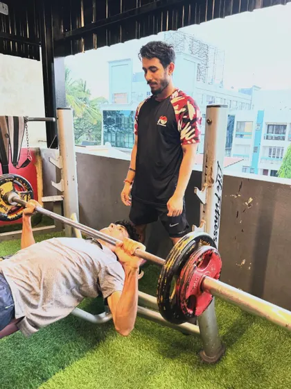 A young athlete performs a bench press with a spotter, demonstrating our commitment to training athletes of all ages with proper supervision.