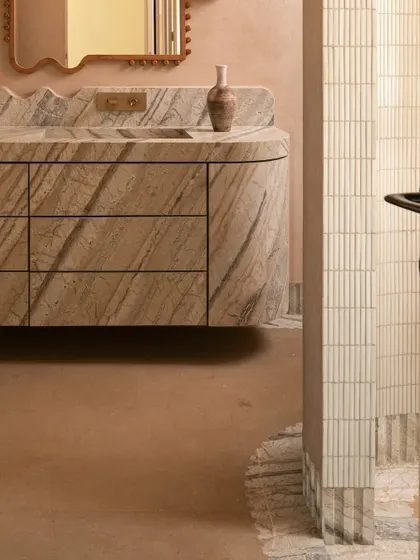 This detail shot highlights the curved corner of the marble vanity and the fluted tilework of the shower partition.