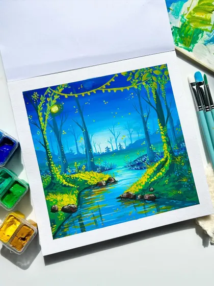 Another view of the magical forest gouache painting, with the paint palette in the background.