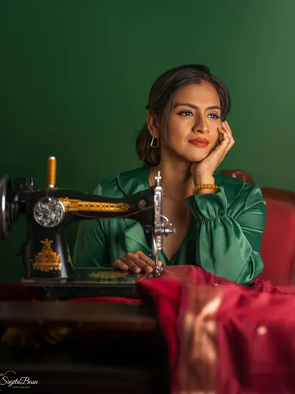 A portrait that tells a story of creativity and heritage. The vintage sewing machine is not just a prop; it's a symbol of craft and tradition. The rich green and red tones, combined with the thoughtful pose, create a deeply narrative and nostalgic image.