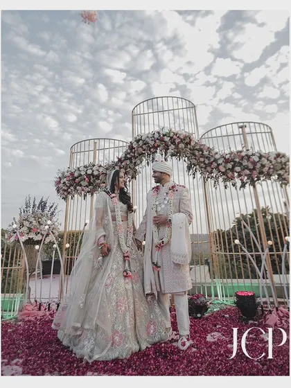 A wide shot of the couple at their beautiful floral mandap.