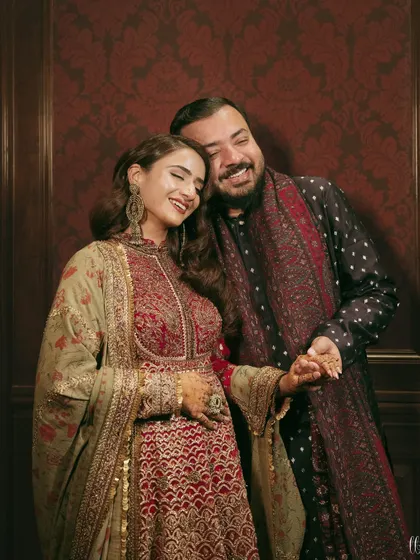 A happy, candid moment between the couple during their Sufi night. Their coordinated outfits in deep, rich tones are perfect for the theme.