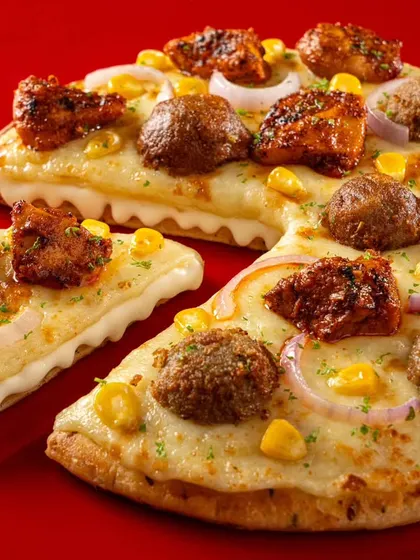 A meatball and chicken tikka pizza from Ovenstory's menu. This shot is composed to highlight the different textures and toppings, appealing to customers looking for a loaded pizza option.