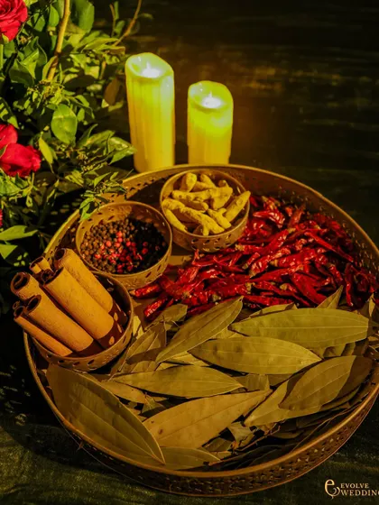 A close-up of the decorative tray of spices, including bay leaves, cinnamon, turmeric, and red chillies. These elements are a nod to timeless Indian traditions of abundance and auspiciousness.