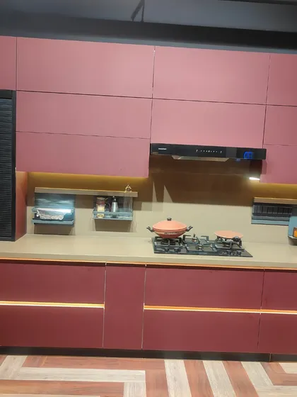A full view of the countertop area in the magenta kitchen. The built-in hob, integrated chimney, and under-cabinet lighting create a highly functional workspace that doesn't compromise on style.