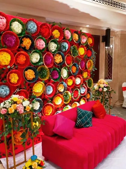 A unique and colorful backdrop for a Mehendi ceremony, created using dozens of baskets filled with dyed flowers. This creative and vibrant wall provided a fantastic photo opportunity for guests.