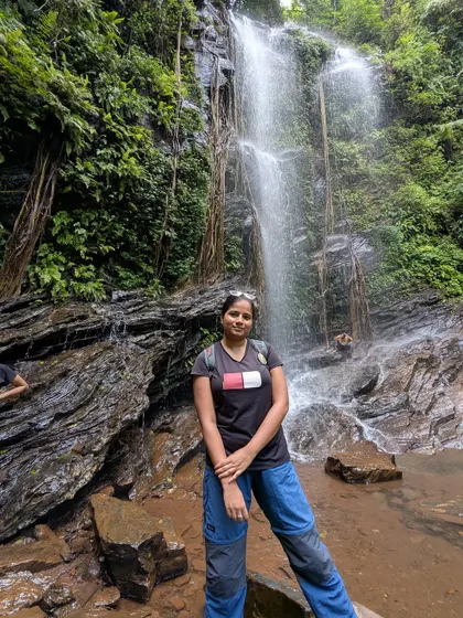 A trekker poses by the rocks at Hidlumane Falls, a perfect photo spot.