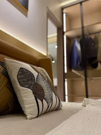 Details make the design. This close-up shot highlights the custom-embroidered cushion and the soft backlighting of the headboard, showcasing our attention to the small touches that elevate a space.