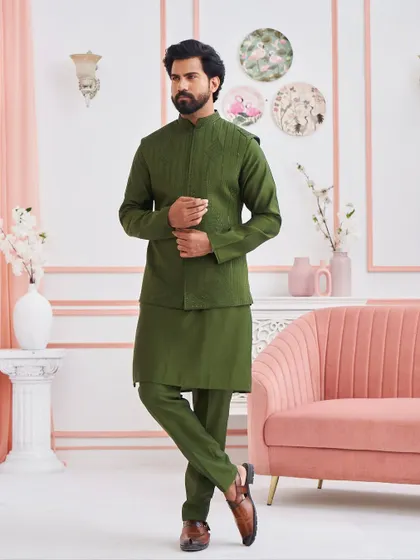 This olive green kurta set, paired with a structured, subtly embroidered jacket, offers a unique and stylish color choice for wedding festivities. It is a modern ensemble rooted in traditional aesthetics.
