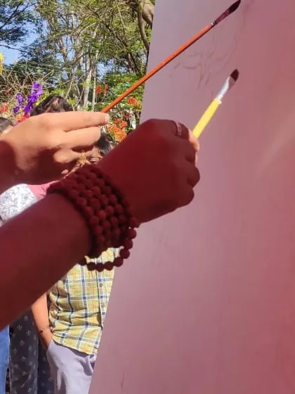 Two brushes, one canvas. A close-up of the moment we began the collaborative acrylic landscape.
