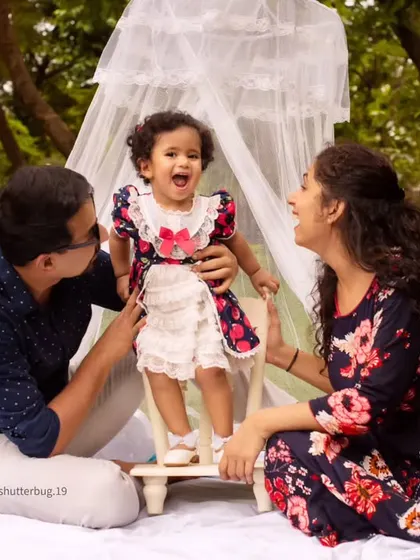 A candid moment of pure joy as parents share a laugh with their daughter during an outdoor family photoshoot.