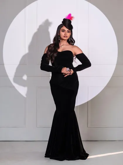 In the spotlight. This full-length shot uses a single, hard light source to create a theatrical, stage-like effect. The black velvet gown and feathered hat add to the vintage glamour of this editorial concept.