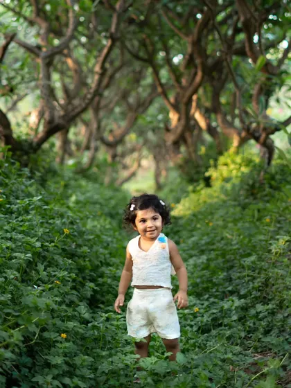 This toddler looks so confident and happy exploring this magical green pathway. I love capturing their adventurous spirit during outdoor photoshoots.