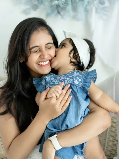 Another angle of a daughter's sweet kiss for her mom. The mother's joyful, closed-eye smile shows just how much she treasures these moments of affection.