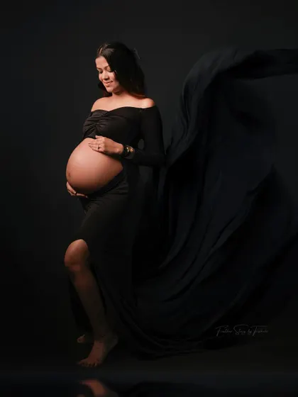 A dramatic and elegant solo portrait in a black flowing gown against a black backdrop. This classic fine art style is truly timeless.