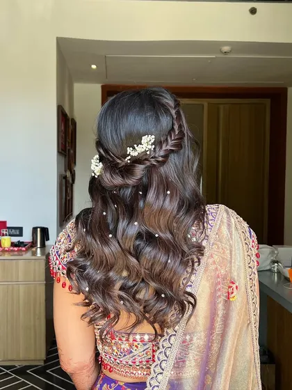 A side view of the half-updo, highlighting the soft waves and the delicate baby's breath woven into the braid.