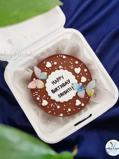 A rich chocolate bento cake decorated simply with white hearts and delicate edible butterflies. It's an elegant and understated design.