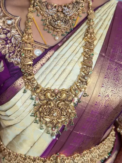 The beauty of a well-draped saree is how it showcases the jewelry. Here, the pleats of this off-white and purple Kanchipuram provide the perfect backdrop for the intricate antique necklace.