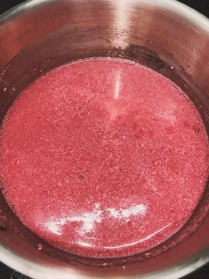 The raspberry mixture cooking gently on the stove. This process requires patience to get the perfect consistency.
