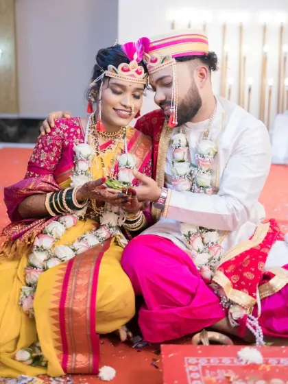 The bride and groom participate in a wedding ritual, their expressions showing a mix of concentration and happiness.
