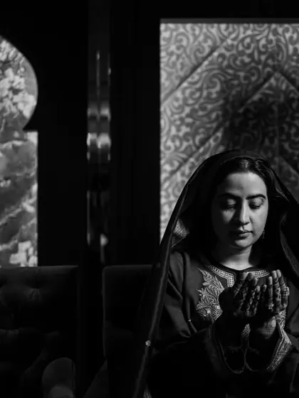 A powerful black and white portrait of a woman in prayer, using dramatic lighting to convey deep emotion and devotion.