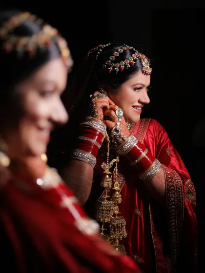 A candid moment of bride Kashika adjusting her earring, her reflection smiling back at her.