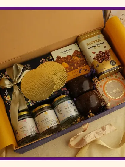 This royal purple hamper is perfect for Navratri or Diwali. The deep purple box is filled with premium snacks like almond brittle and other treats, wrapped in yellow tissue paper for a vibrant contrast.