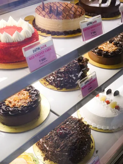 A peek inside our display case, showcasing the variety of eggless cakes we have ready for you every day. You can see our Red Velvet, Black Forest, and Coffee Mocha cakes waiting for a home.