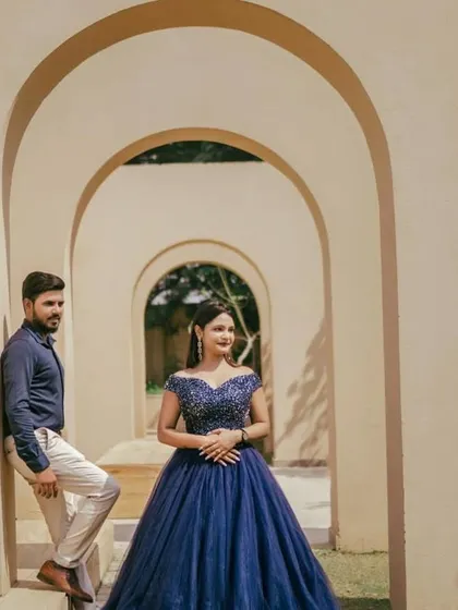 A couple posing in a grand archway, featuring a sparkling navy blue ball gown. This dress is perfect for an elegant pre-wedding theme that requires a touch of royalty.