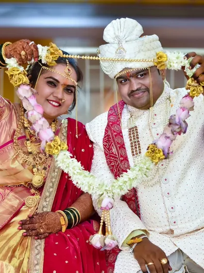 The bride and groom playfully hold up their Varmala garlands, a classic portrait capturing their happiness after the exchange.