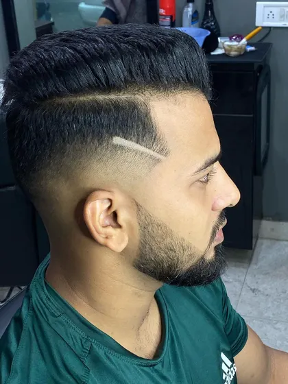 A profile shot that clearly shows the sharp line design and the clean fade. The beard is also neatly trimmed to complement the haircut.