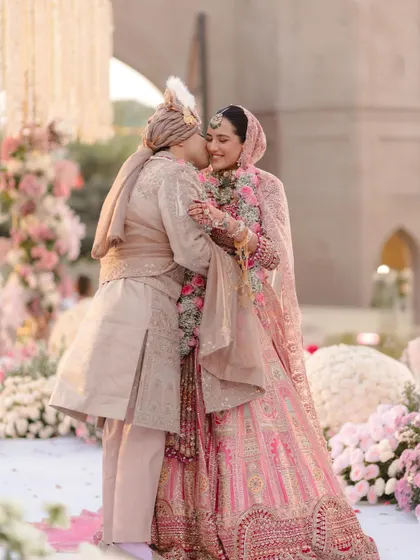 A sweet kiss on the cheek. A classic, romantic moment captured beautifully against the backdrop of their pastel-themed wedding.