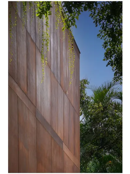 The rust-colored facade panels are softened by cascading greenery, illustrating my approach of letting nature become an integral part of the architectural expression.