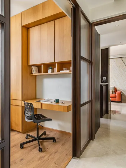 This view shows how the guest study area is neatly tucked away, accessible through a modern frosted glass sliding door, creating a private and functional workspace.