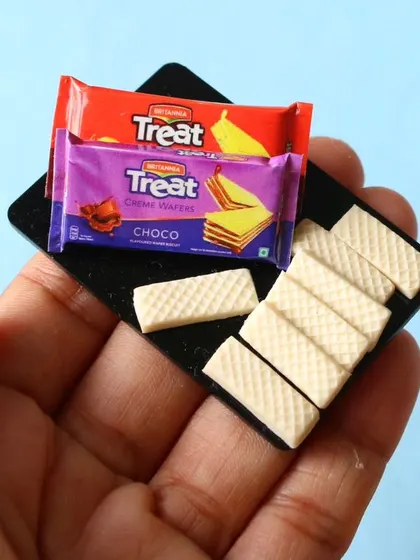A close-up of a miniature Treat wafer biscuit packet and the tiny, detailed wafers.