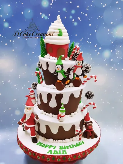 A whimsical, multi-tiered Christmas-themed birthday cake. This creation features playful penguins, candy canes, snow-dusted tiers, and a giant cupcake topper, perfect for a December birthday.