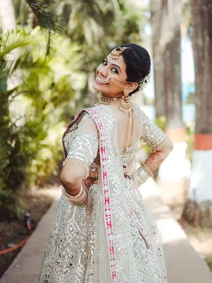 A classic bridal pose, looking back over the shoulder, highlighting the intricate work on her lehenga and her joyful expression.