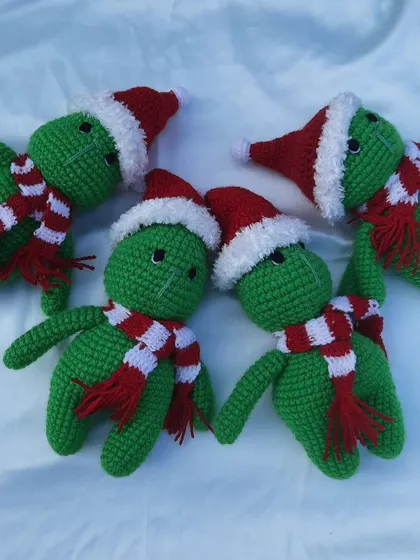 A group of green Grinch-like creatures wearing Santa hats and scarves, a fun and festive creation for Christmas.