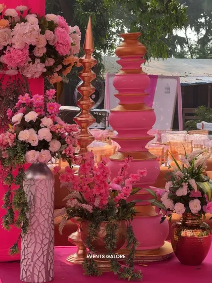 A close-up of the decor details, featuring traditional stacked pots and a 'diya' sculpture in pink and gold, surrounded by beautiful floral arrangements that tied the whole look together.