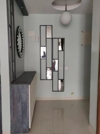 This foyer area features a shoe rack and decorative mirror, leading into the eclectic kitchen space. The design elements are chosen to create a cohesive journey from the entrance.