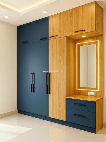 A two-tone wardrobe design combining a bold blue with a natural wood finish. I integrated a compact, backlit dressing mirror and drawers into the unit to save space.